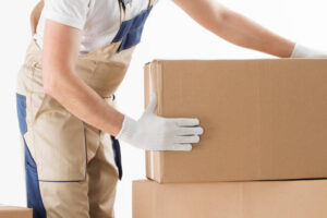 Relocation services concept. Mover in uniform with cardboardboxes isolated on white background.